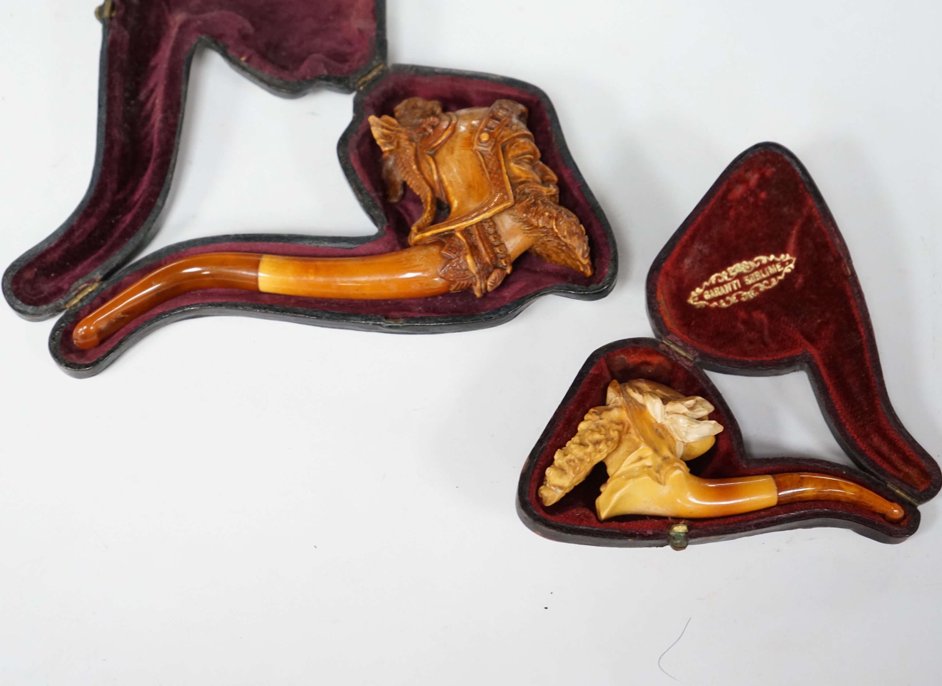 Two cased novelty Meerschaum pipes, their bowls modelled as an Arthurian knight and another a bearded man, both with amber mouthpieces, largest 16cm long
